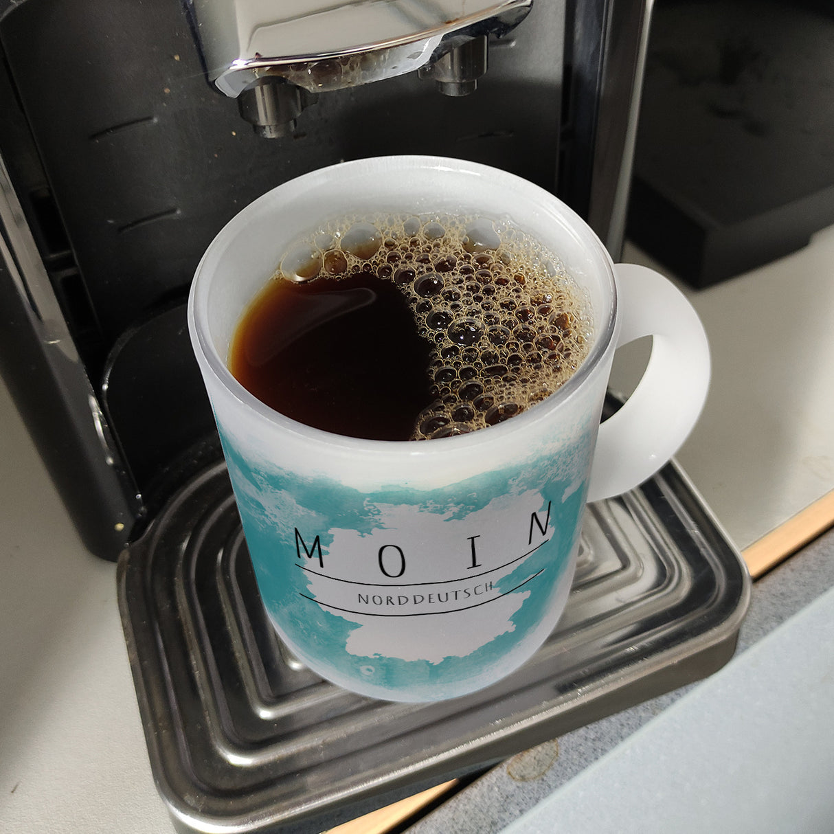 Hallo auf Norddeutsch Moin lustiger Kaffeebecher mit blauem Hintergrund