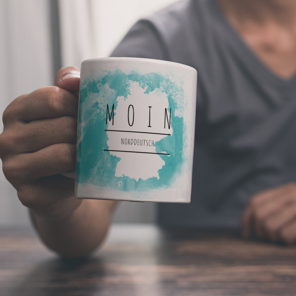 Hallo auf Norddeutsch Moin lustiger Kaffeebecher mit blauem Hintergrund