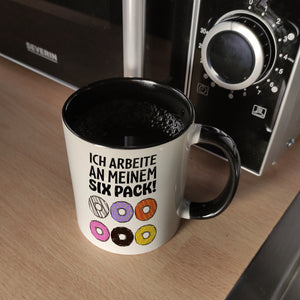Ich arbeite an meinem Six Pack Kaffeebecher mit bunten Donuts