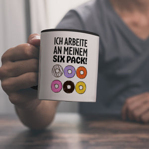 Ich arbeite an meinem Six Pack Kaffeebecher mit bunten Donuts