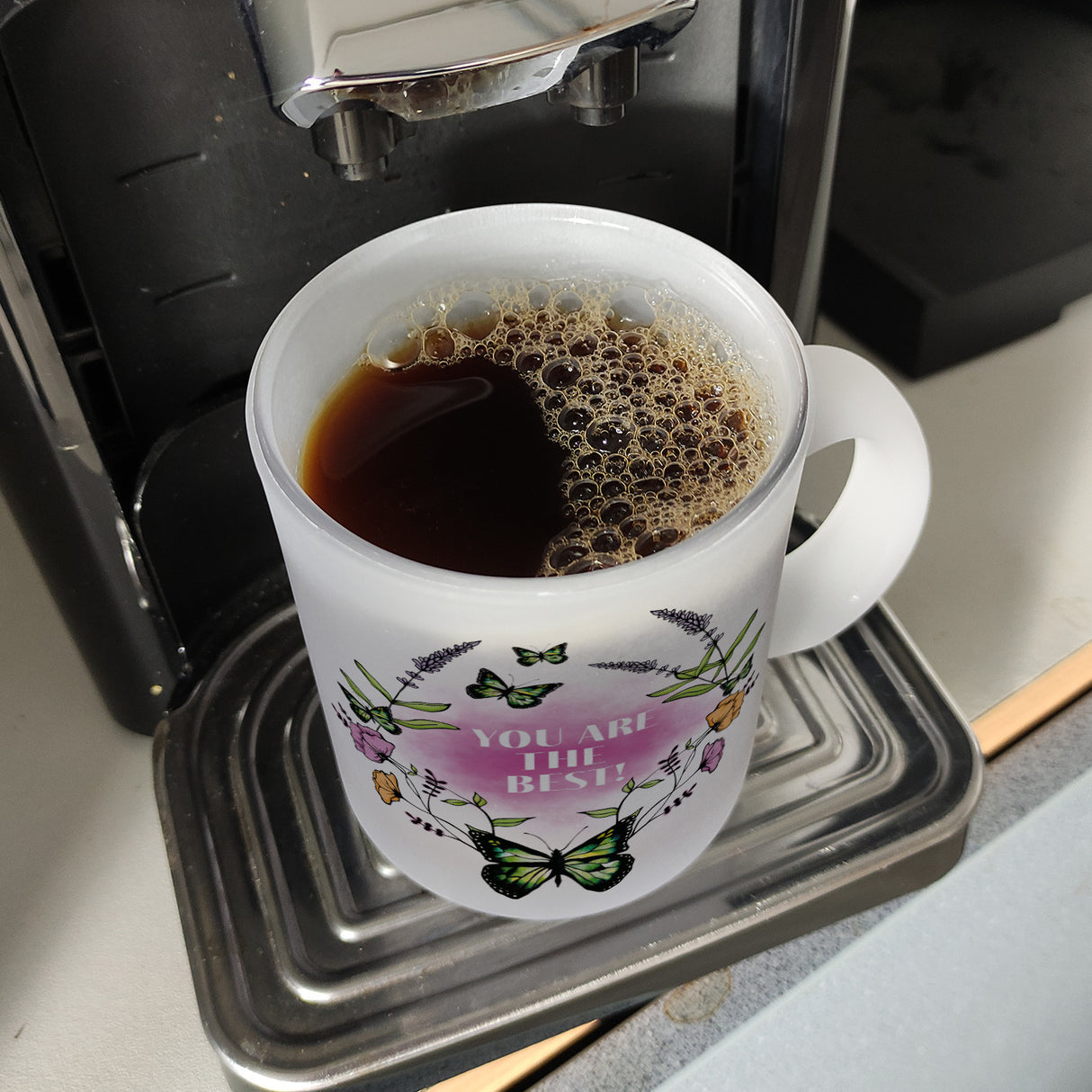 Kaffeebecher mit motivierenden Worten und Blumenrahmen mit Schmetterlingen