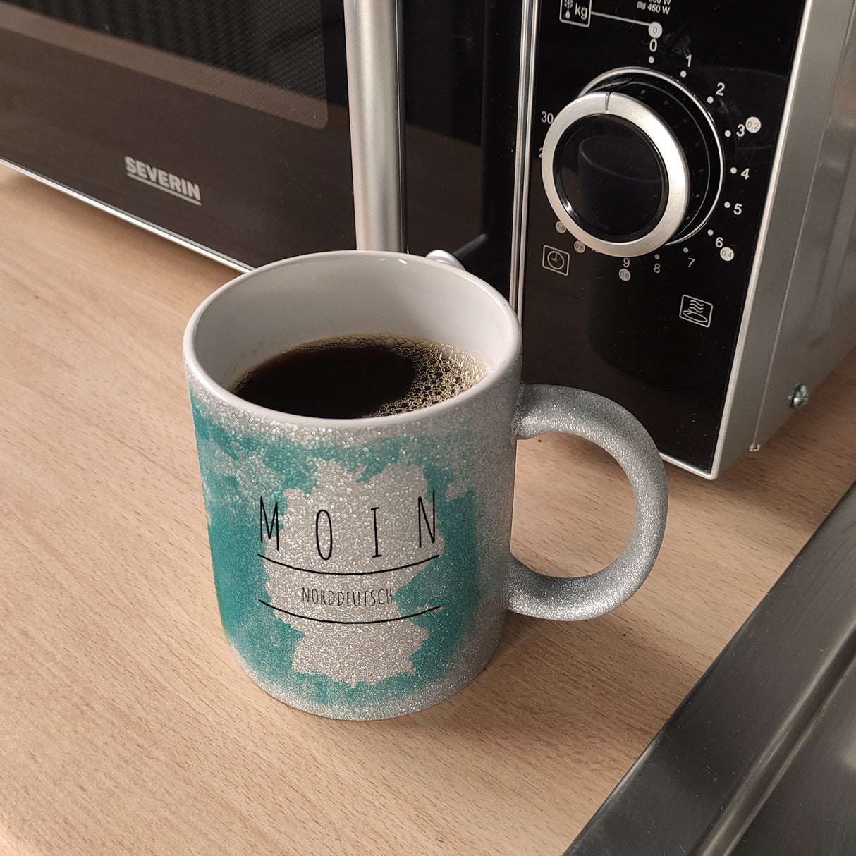 Hallo auf Norddeutsch Moin lustiger Kaffeebecher mit blauem Hintergrund