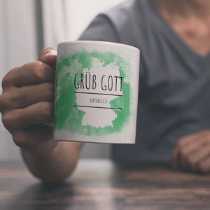 Hallo auf Bayerisch Grüß Gott lustiger Kaffeebecher mit grünem Hintergrund